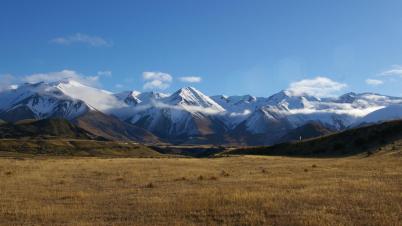 Snowy mountains shrouded in cloud with a blue sky background. Snowy mountains shrouded in cloud with a blue sky background.